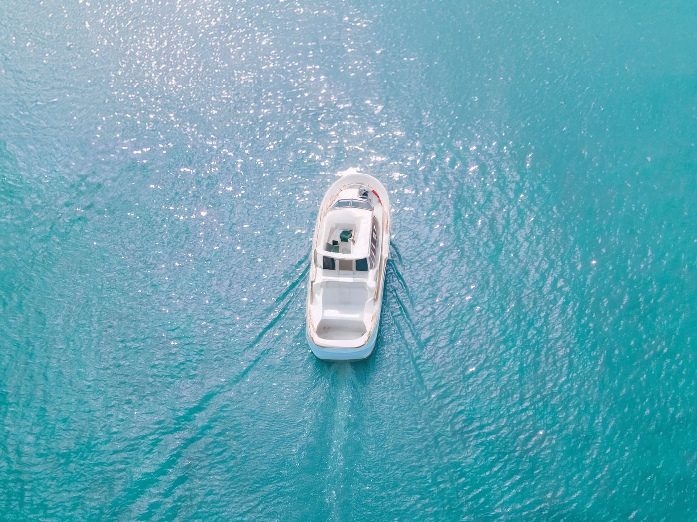 An aerial view of a motorboat on clear turquoise water